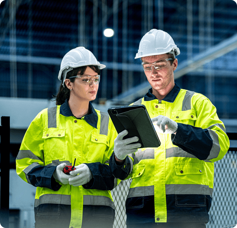 Workers in safety gear using tablet.