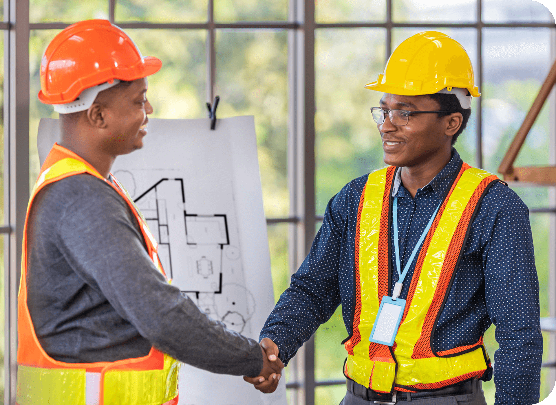 Two construction workers shaking hands indoors.
